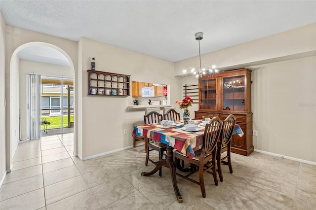 732 Kensington Lake Cir, Brandon, FL 33511 - dining room featuring baseboards, a chandelier, and arched walkways