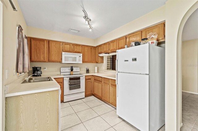 732 Kensington Lake Cir, Brandon, FL 33511 - kitchen featuring white appliances, a sink, arched walkways, light tile patterned floors, and light countertops