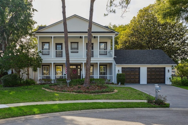 neoclassical home with a porch, concrete driveway, a garage, a front yard, and a balcony