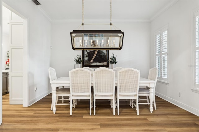 dining area with light wood-style floors, ornamental molding, and baseboards