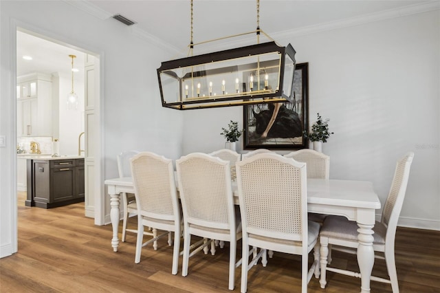 dining room featuring crown molding, light wood finished floors, and baseboards