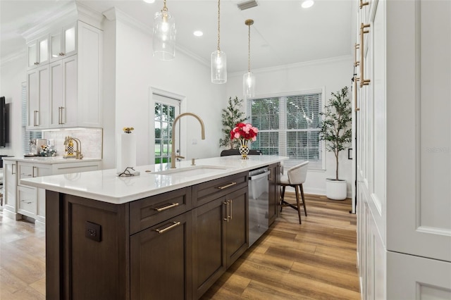 kitchen with a sink, light countertops, white cabinetry, dishwasher, and ornamental molding