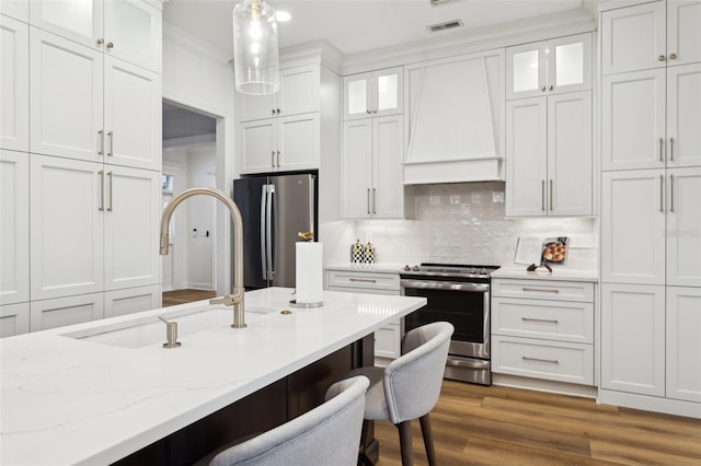 kitchen with stainless steel appliances, a sink, premium range hood, a breakfast bar, and white cabinets