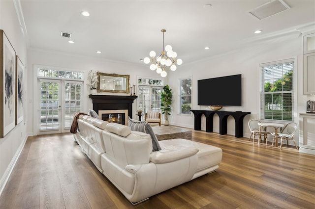 living room with crown molding, healthy amount of natural light, wood finished floors, a glass covered fireplace, and baseboards