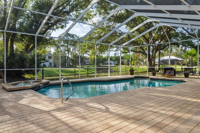 view of pool featuring a patio, glass enclosure, a pool with connected hot tub, and a lawn