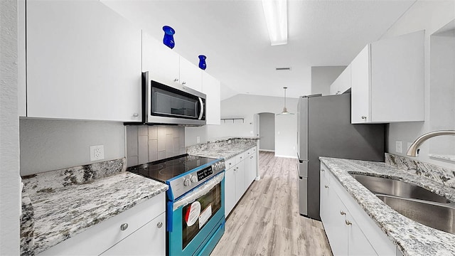 2675 Cherokee St, North Port, FL 34286 - kitchen featuring appliances with stainless steel finishes, a sink, light wood finished floors, white cabinets, and vaulted ceiling