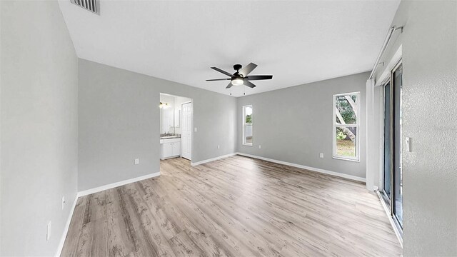 2675 Cherokee St, North Port, FL 34286 - unfurnished bedroom featuring light wood-style flooring, baseboards, ensuite bathroom, and ceiling fan