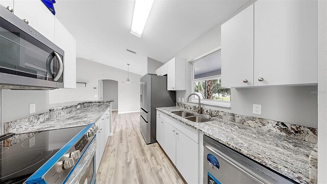 2675 Cherokee St, North Port, FL 34286 - kitchen with appliances with stainless steel finishes, a sink, light wood-style flooring, light stone countertops, and white cabinets