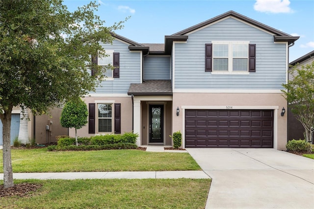 traditional-style home with a garage, stucco siding, concrete driveway, roof with shingles, and a front lawn