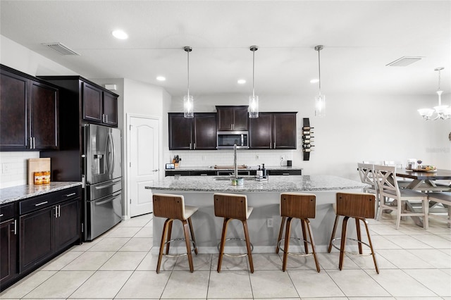 kitchen featuring appliances with stainless steel finishes, visible vents, tasteful backsplash, and a kitchen bar