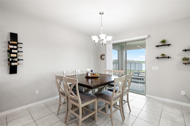 dining room featuring a chandelier, a water view, baseboards, and light tile patterned flooring