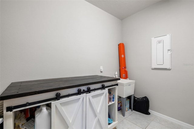 laundry area featuring baseboards, light tile patterned floors, and electric panel
