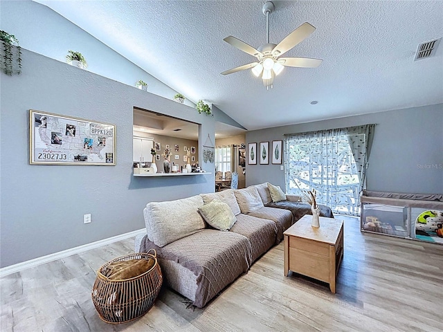 living area featuring vaulted ceiling, visible vents, wood finished floors, and a ceiling fan