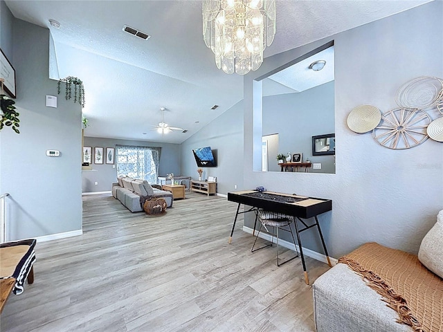 living room with lofted ceiling, baseboards, visible vents, ceiling fan with notable chandelier, and wood finished floors