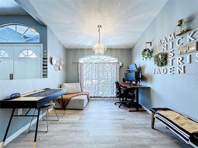 office space featuring a textured ceiling, wood finished floors, baseboards, and a notable chandelier