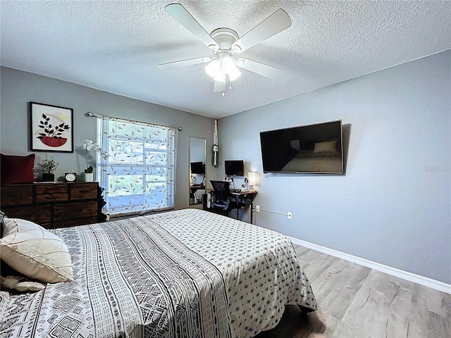 bedroom with baseboards, ceiling fan, a textured ceiling, and wood finished floors