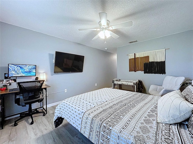 bedroom featuring a textured ceiling, visible vents, ceiling fan, light wood-style flooring, and baseboards