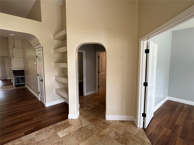 1608 Fox Glen Ct, Winter Springs, FL 32708 - hallway featuring arched walkways, baseboards, a towering ceiling, and wood finished floors