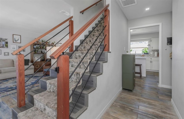 stairway with visible vents, wood finished floors, and baseboards