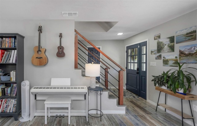 foyer entrance with stairway, baseboards, visible vents, and wood finished floors