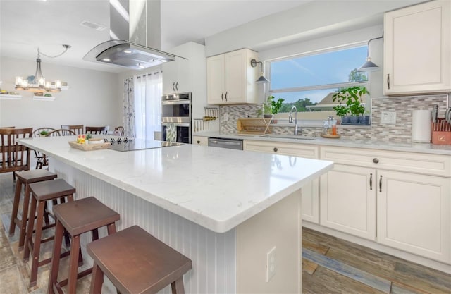 kitchen with a sink, stainless steel appliances, tasteful backsplash, island exhaust hood, and a center island