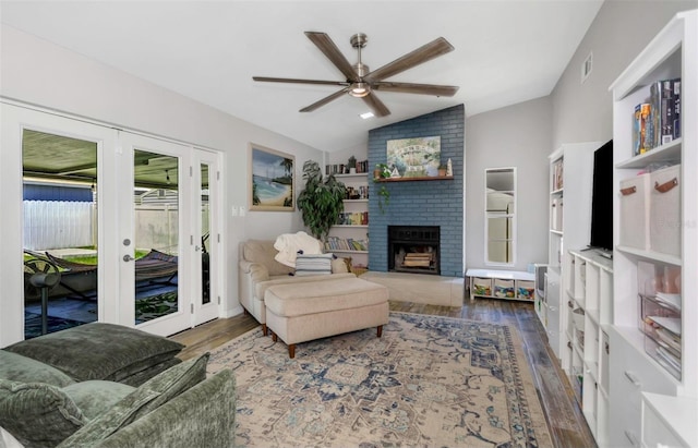 living area featuring wood finished floors, a brick fireplace, visible vents, ceiling fan, and lofted ceiling
