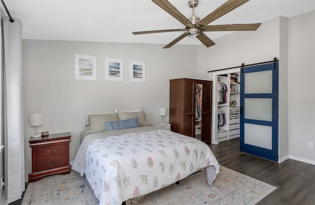 bedroom featuring wood finished floors, a closet, a barn door, baseboards, and vaulted ceiling