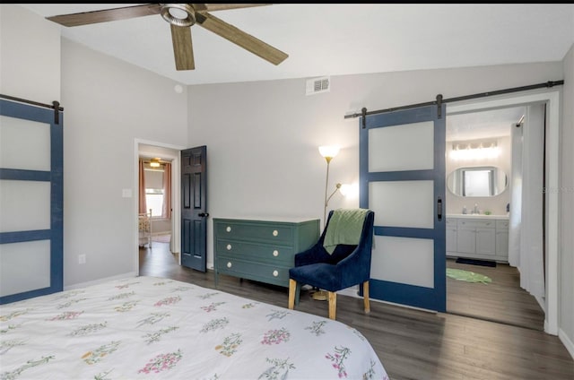 bedroom featuring lofted ceiling, a barn door, visible vents, and wood finished floors