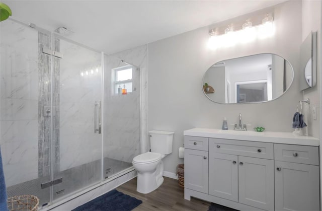 bathroom with toilet, a marble finish shower, wood finished floors, and vanity