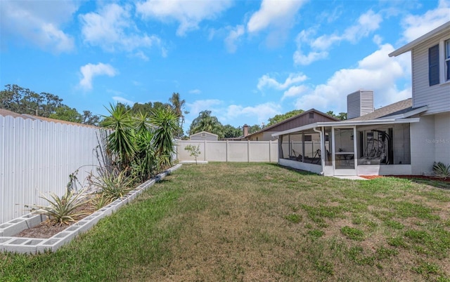 view of yard featuring a sunroom and a fenced backyard