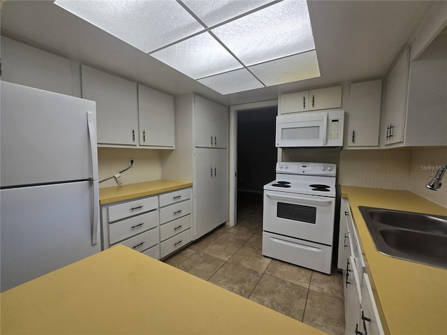 kitchen featuring light countertops, light tile patterned flooring, a sink, and white appliances