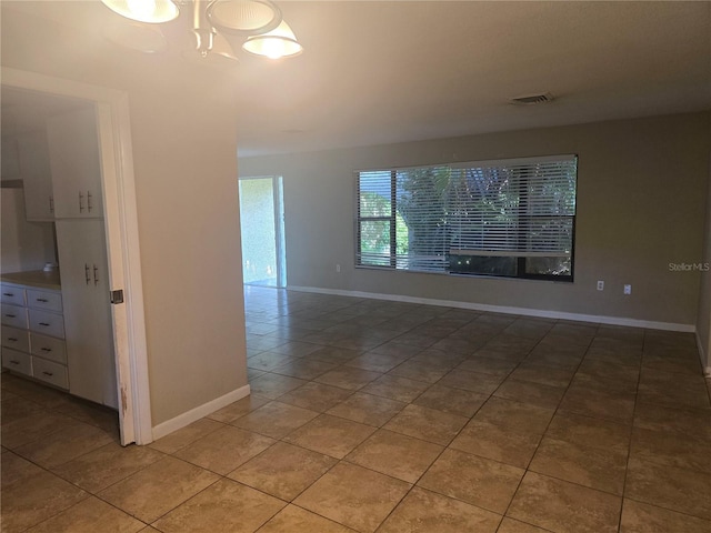 unfurnished room featuring a chandelier, baseboards, light tile patterned flooring, and visible vents