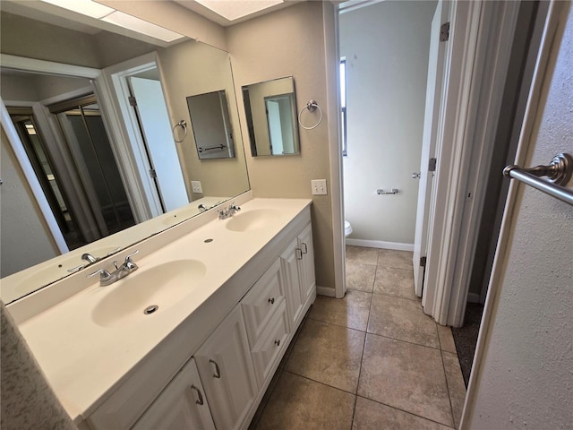 full bath featuring double vanity, toilet, tile patterned flooring, and a sink