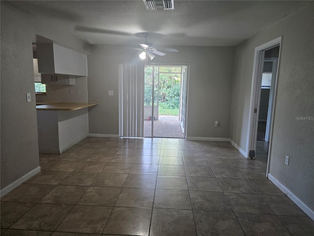 unfurnished dining area featuring ceiling fan, dark tile patterned flooring, baseboards, and visible vents