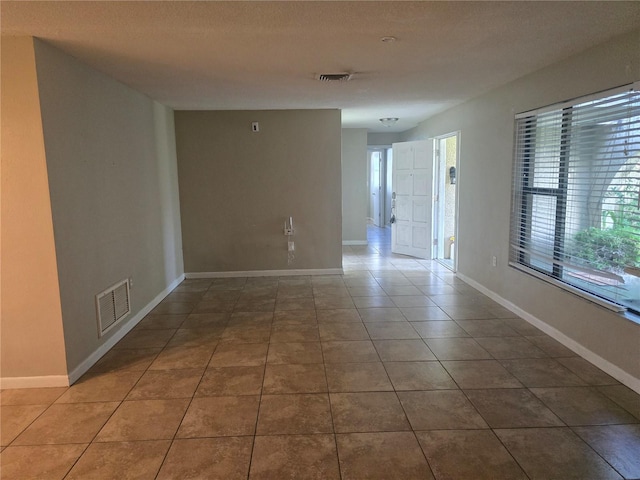 tiled spare room featuring baseboards and visible vents