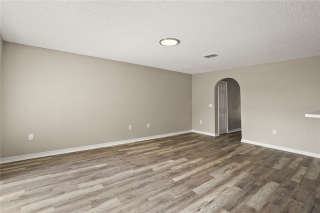 11323 Ivy Flower Loop, Riverview, FL 33578 - empty room featuring a textured ceiling, baseboards, dark wood finished floors, visible vents, and arched walkways