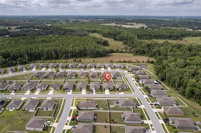 aerial view of property's location featuring a forest and nearby suburban area