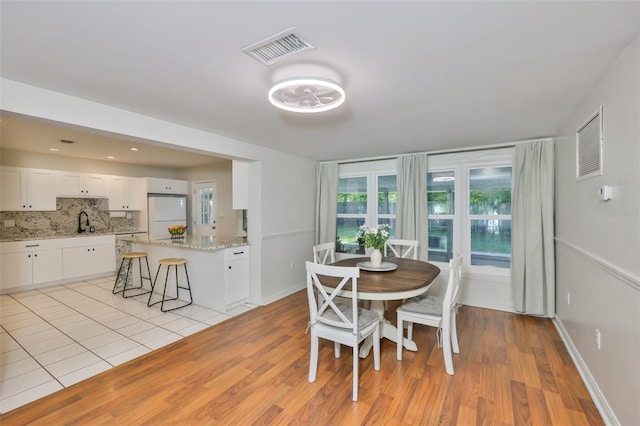 dining space with light wood-style floors, visible vents, and baseboards