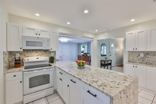 kitchen with a peninsula, light tile patterned flooring, white appliances, and tasteful backsplash