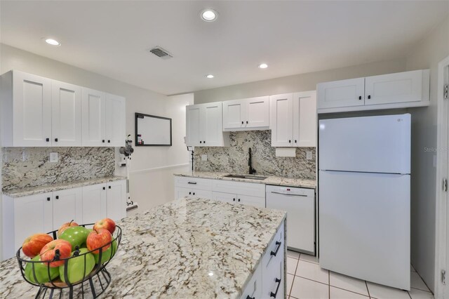kitchen with a sink, white appliances, visible vents, white cabinetry, and backsplash