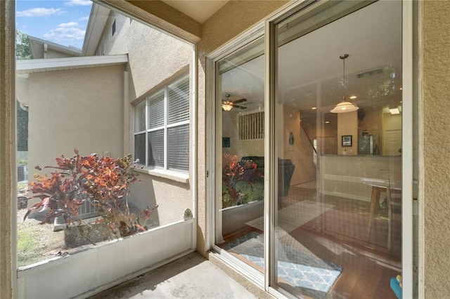 exterior space featuring ceiling fan, a textured wall, and wood finished floors