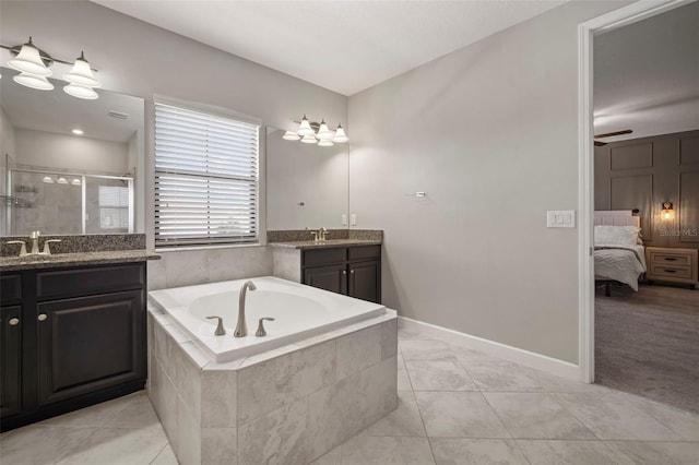 ensuite bathroom featuring a shower stall, tile patterned floors, a bath, two vanities, and baseboards