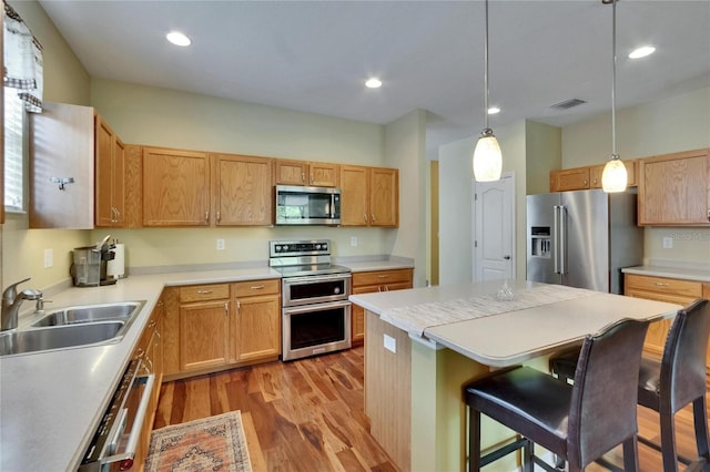 kitchen featuring a sink, stainless steel appliances, visible vents, a kitchen bar, and light wood-style floors
