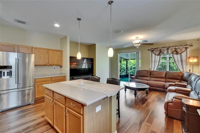 kitchen featuring open floor plan, light countertops, high end fridge, and light wood-style floors