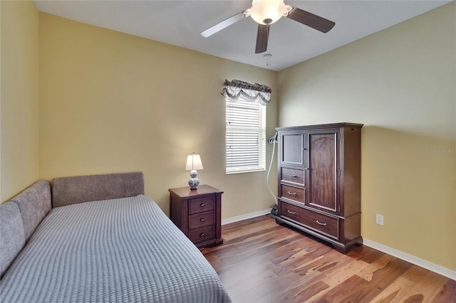 bedroom with a ceiling fan, wood finished floors, and baseboards