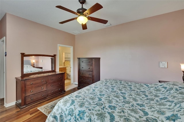 bedroom with connected bathroom, visible vents, wood finished floors, and a ceiling fan