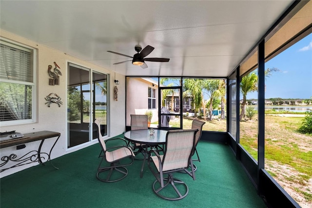sunroom / solarium with a water view, outdoor dining space, and a ceiling fan