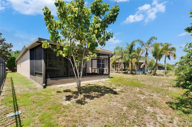 rear view of property with a yard, a sunroom, and fence