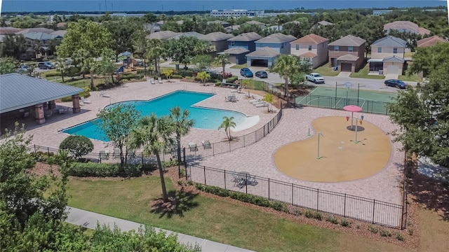 community pool with a lawn, a residential view, and fence