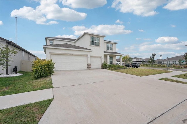 traditional home featuring stucco siding, driveway, a front yard, and a garage